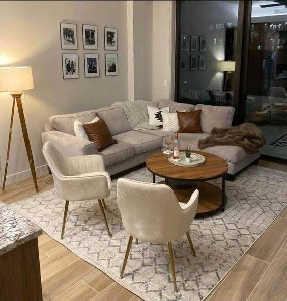 A small apartment living room with a sofa and chairs featuring exposed wooden legs.