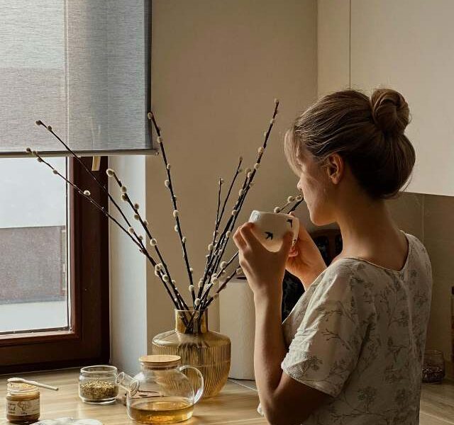 A woman enjoying her coffee while gazing out the window.