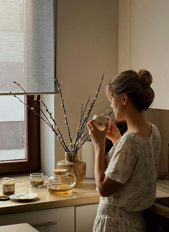 A woman enjoying her coffee while gazing out the window.