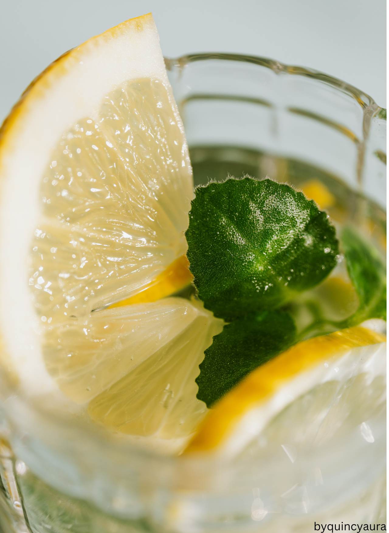 A glass of fresh water with lemon slices on a bedside table in soft morning light