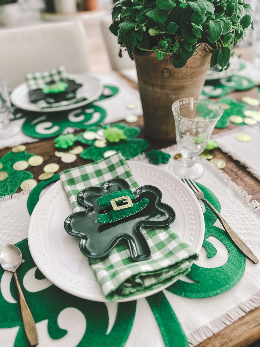 Neutral and green patterned linen napkins folded neatly on plates with a sprig of greenery.