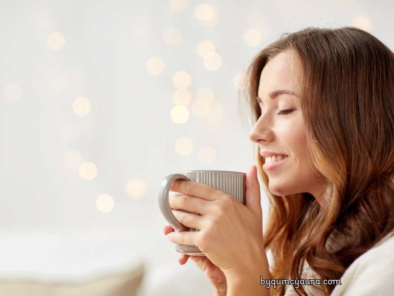 A lady smiling and drinking coffee.
