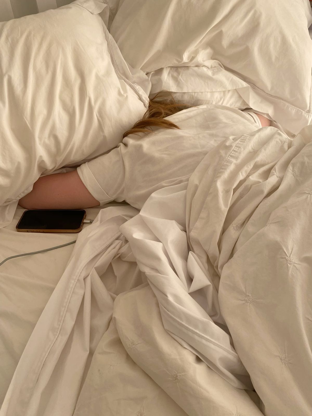 A person placing their phone face down on the bed to disconnect before sleep.