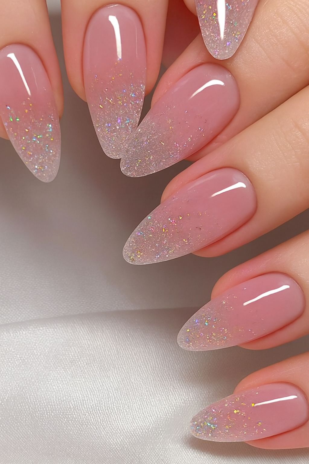 almond nails with a soft pink ombre fade and subtle glitter on the tips