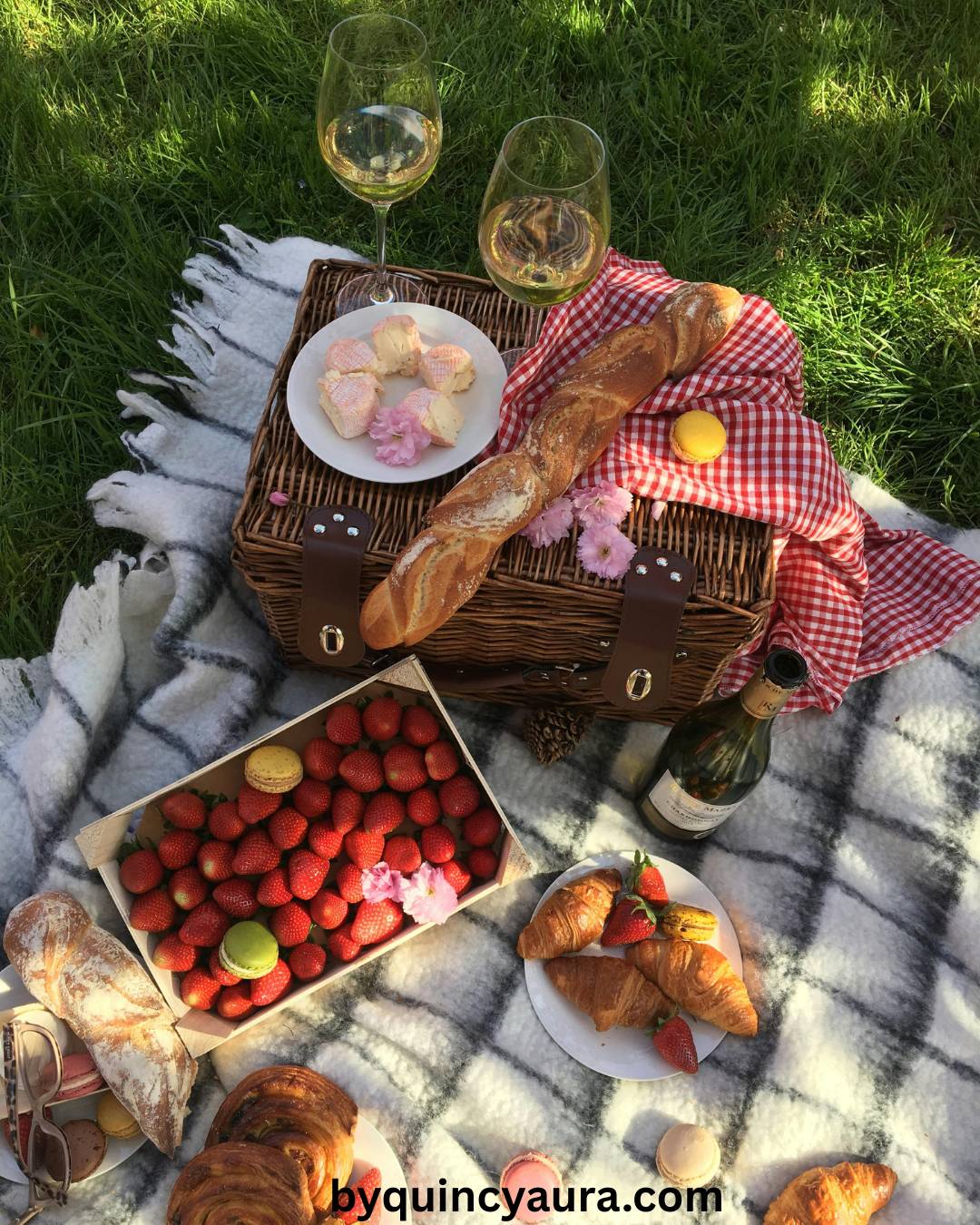 A neatly packed picnic basket with simple foods like fruit, bread, pastries, and drinks laid out on a blanket.