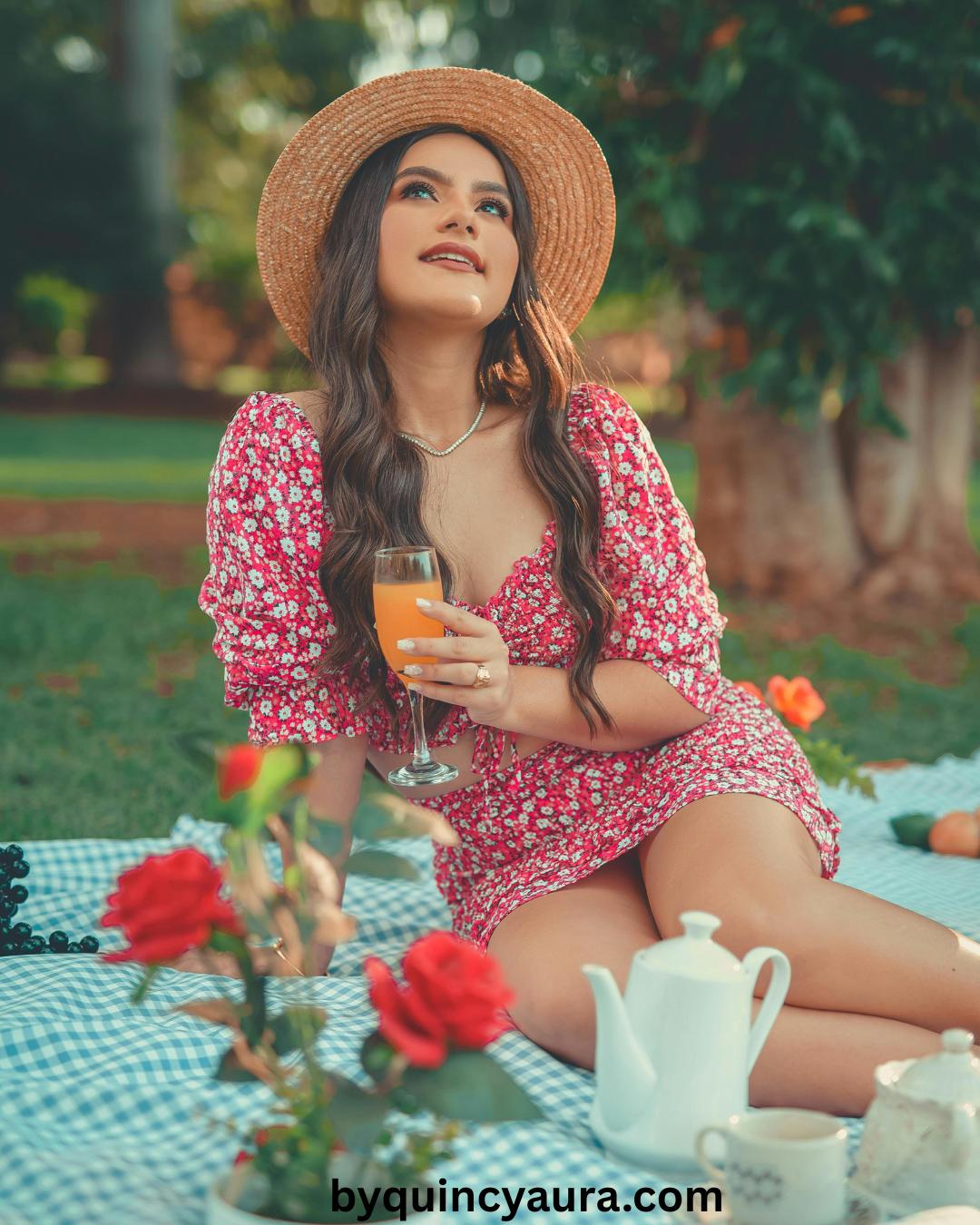 A woman wearing a flowy dress with flat sandals, sitting on a picnic blanket with flowers and snacks.