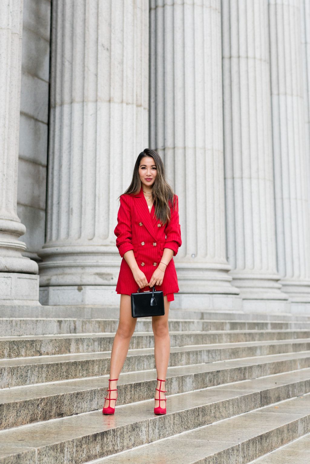A woman wearing a red dress with a belted blazer styled for a chic office or daytime look.