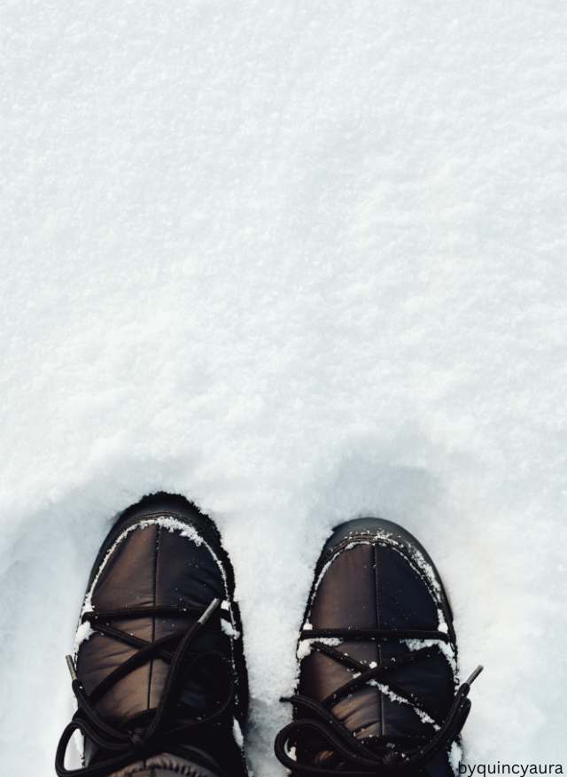 A pair of rubber-soled winter boots on a snowy or icy street.