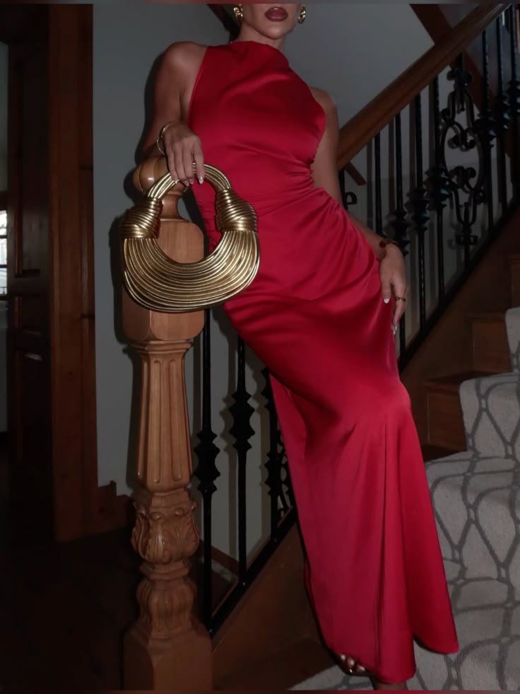 A lady wearing a long red dress with a gold bag