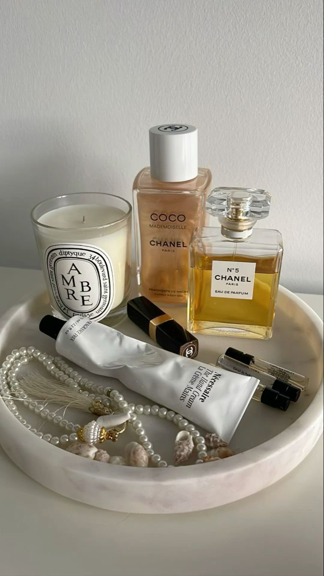 arranged tray on a bedside table with perfume, lip balm, and jewelry on it.