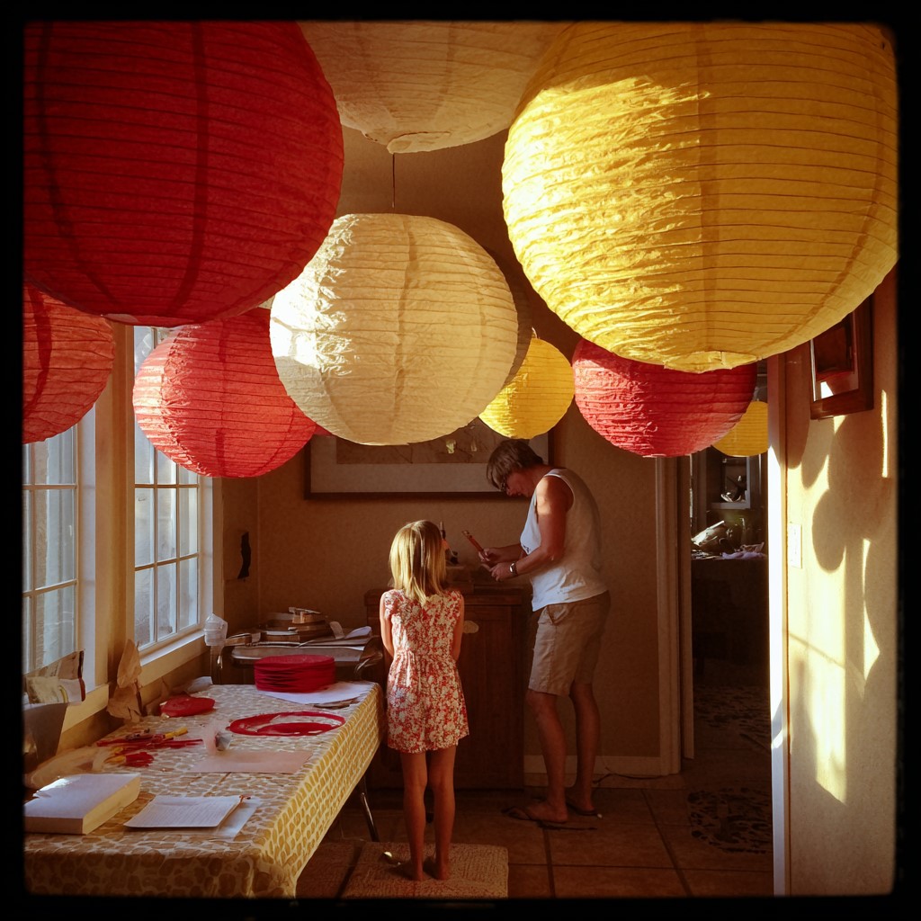 photo of a cozy home setting decorated with handmade paper lanterns in deep red, soft gold, and cream colors.