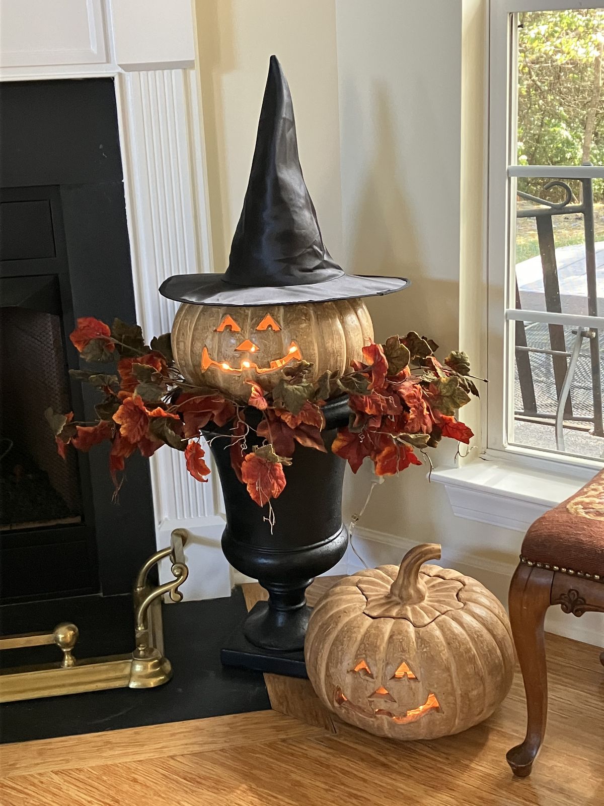 A black hat can sit on top of a pumpkin arrangement